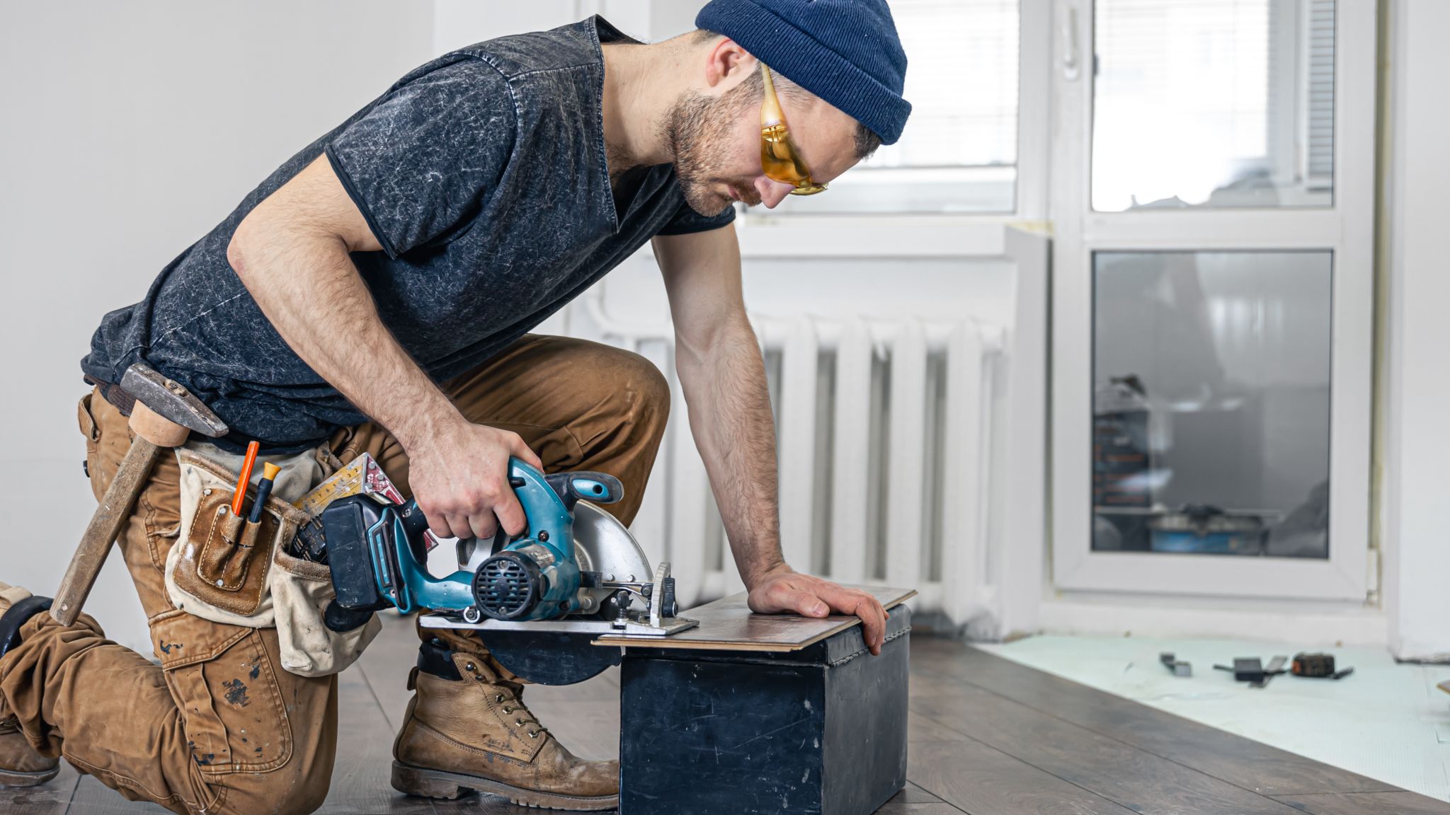 Handwerker mit Stichsäge schneidet ein Stück Laminat