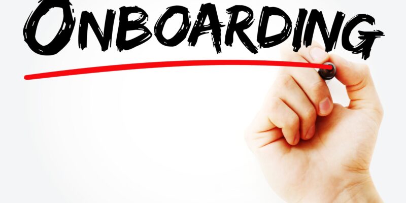 Eine Hand unterstreicht das Wort Onboarding mit einem Stift