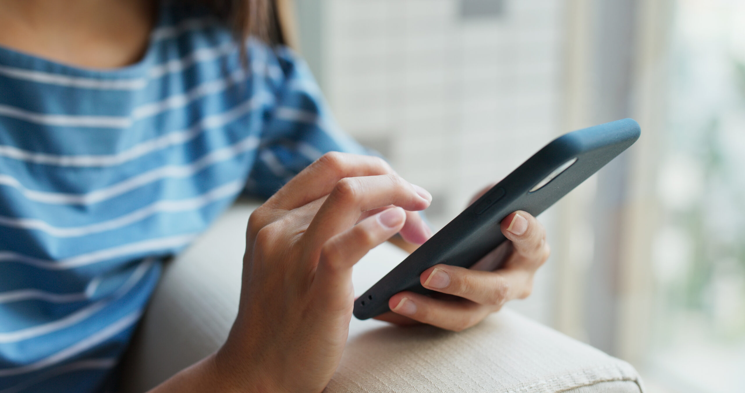 Nahaufnahme einer Frau bei der Benutzung eines Mobiltelefons zu Hause